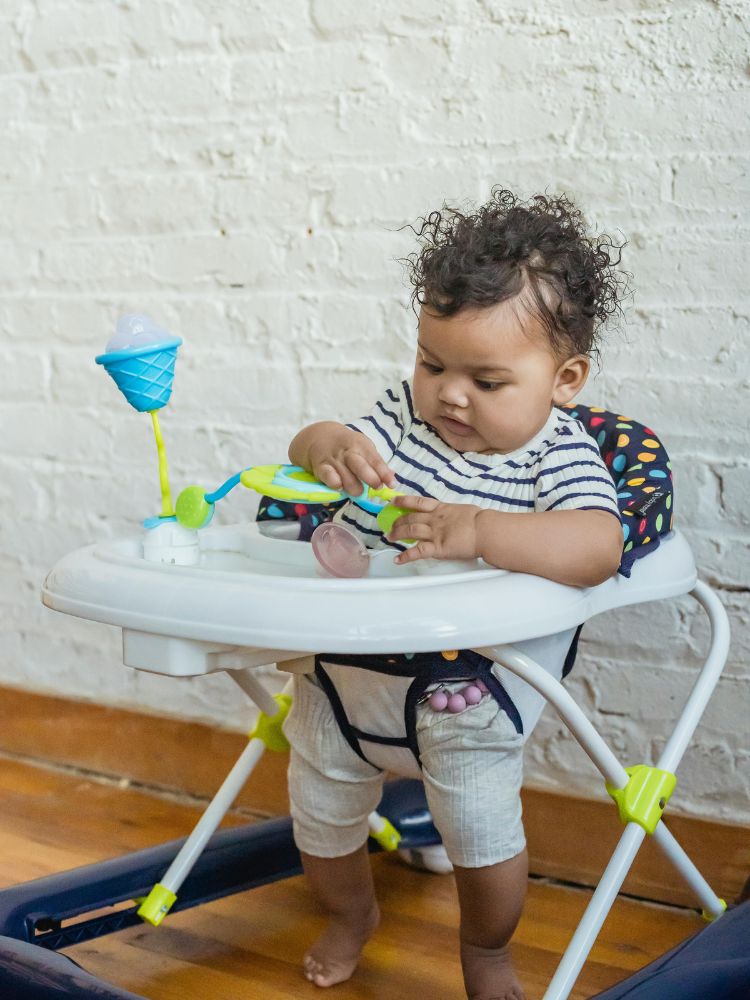 imagem mostra um andador de bebê com uma menina brincando nele