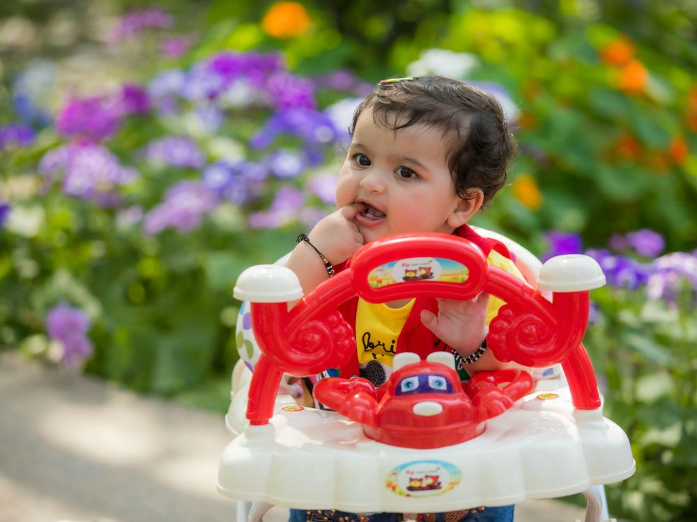 menina em um andador de bebê vermelho no jardim