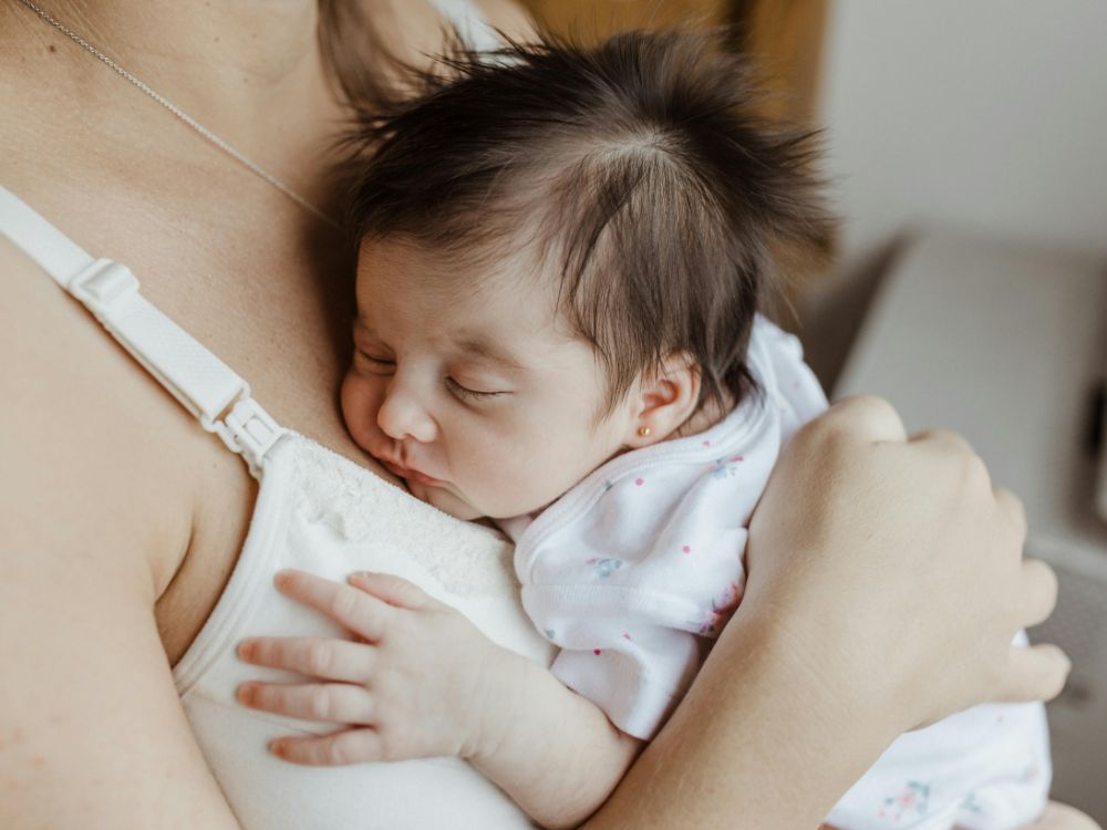 bebê de 1 mês dormindo tranquilo no colo de sua mãe