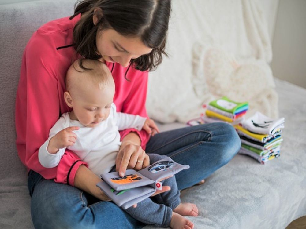 mãe estimulando a comunicação do seu bebê de 3 meses através da leitura de um livro