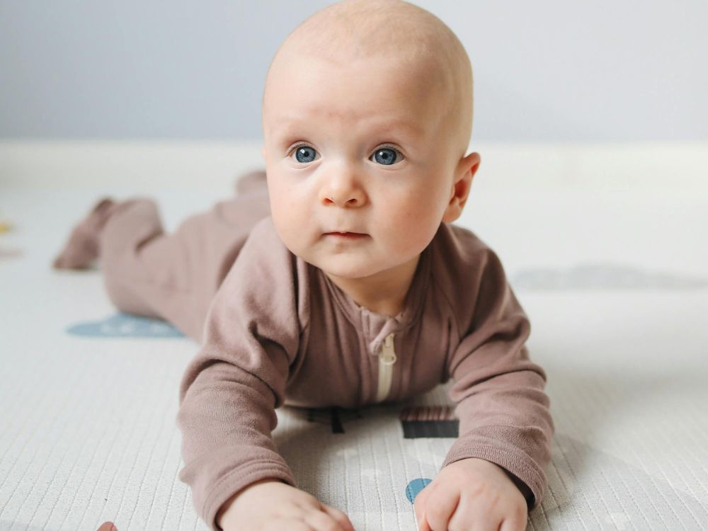 bebê de 6 meses de bruços estimulando a força das costas e do pescoço