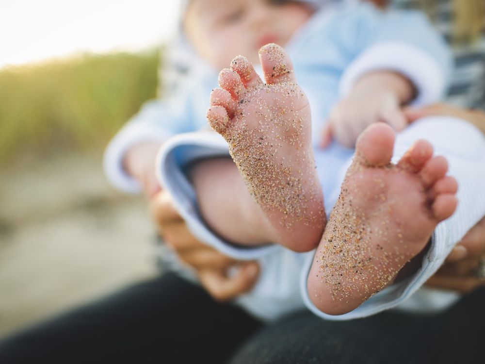 bebê de 6 meses com os pés sujos de areia