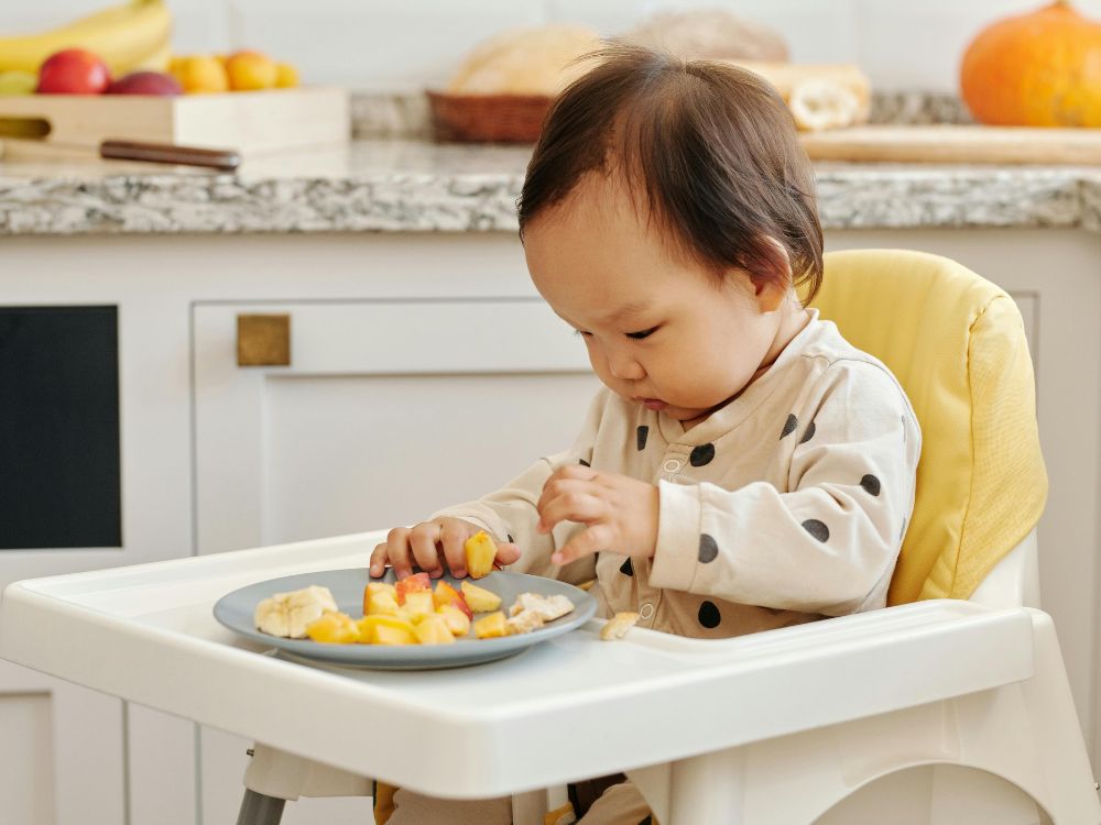 bebê comendo pequenos pedaços de alimentos na introdução alimentar