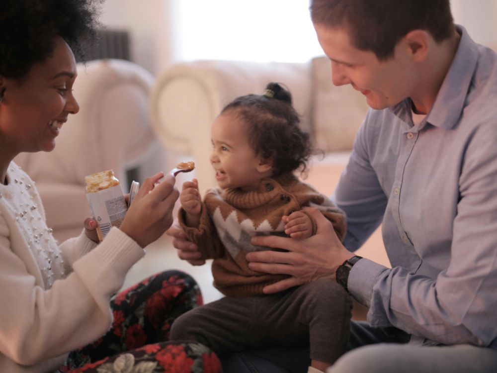 Mãe e pai de bebê realizando a introdução alimentar dela