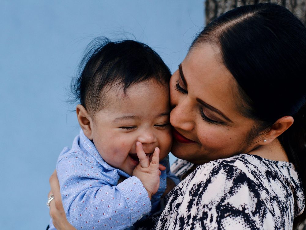 mãe segurando seu bebê no colo sorrindo