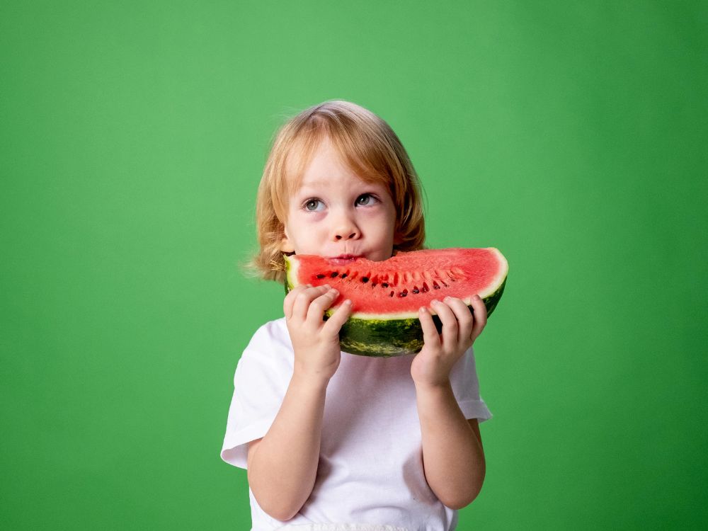 criança comendo melancia. essa é uma estratégia para proteger bebês e crianças no tempo seco