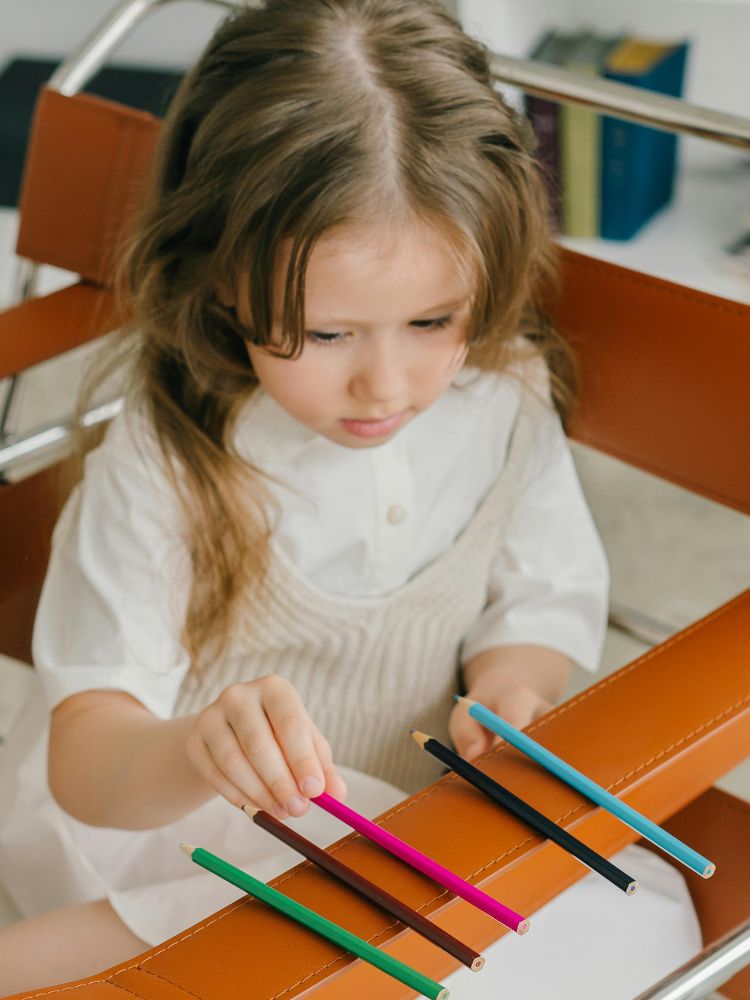 menina enfileirando lápis de cor ilustrando sinais de autismo em bebês