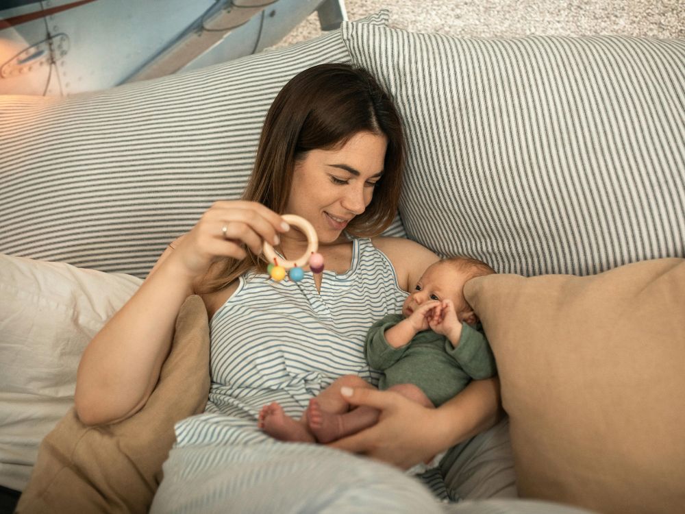 mãe estimulando a audição de um bebê de 3 meses utilizando um chocalho