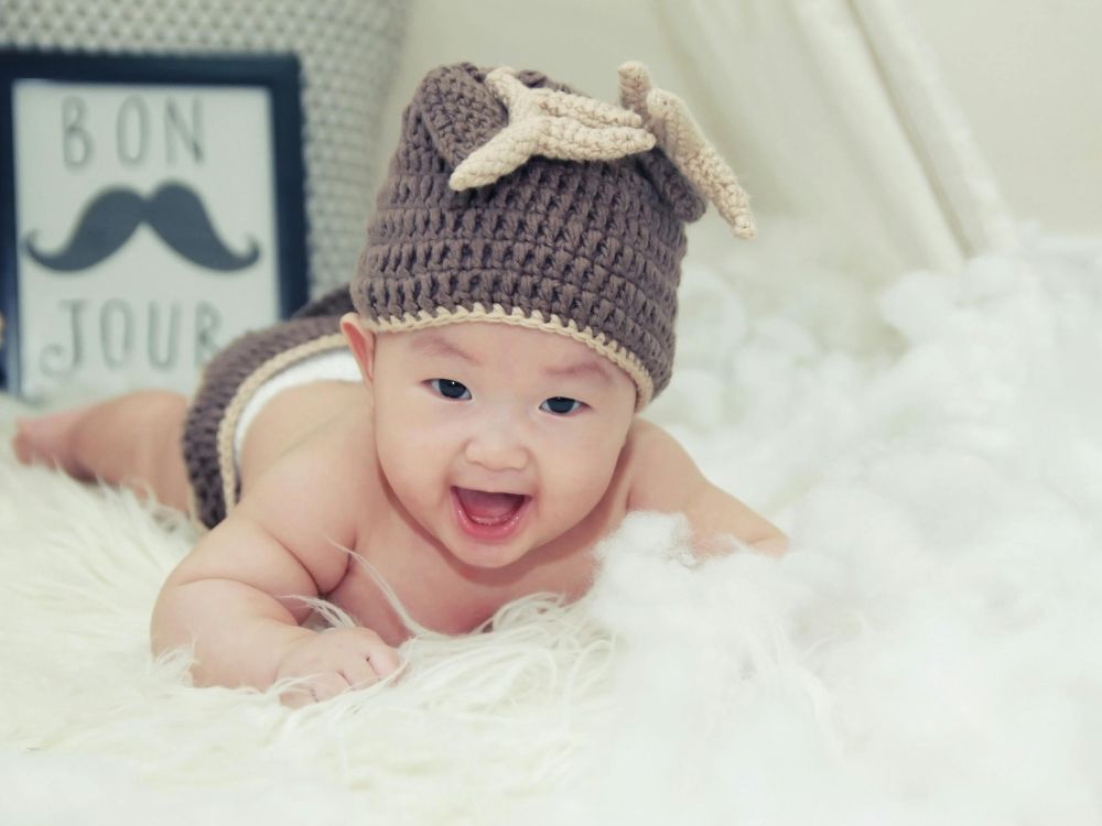 bebê de 3 meses realizando o tummy time com touca de crochê