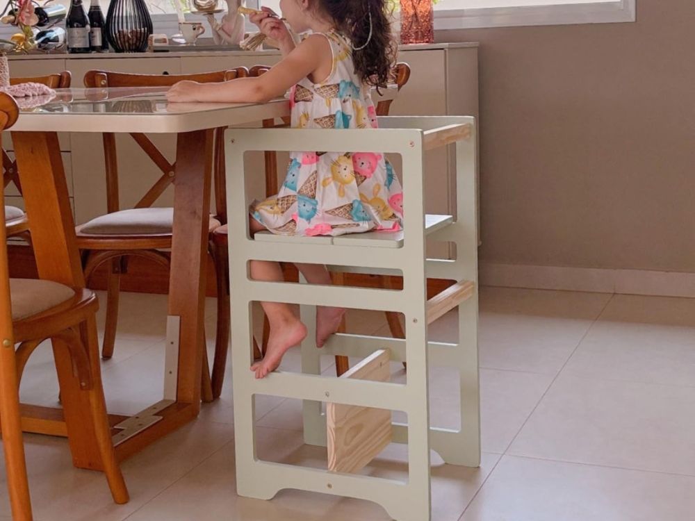 menina sentada na torre de aprendizagem comendo sua refeição